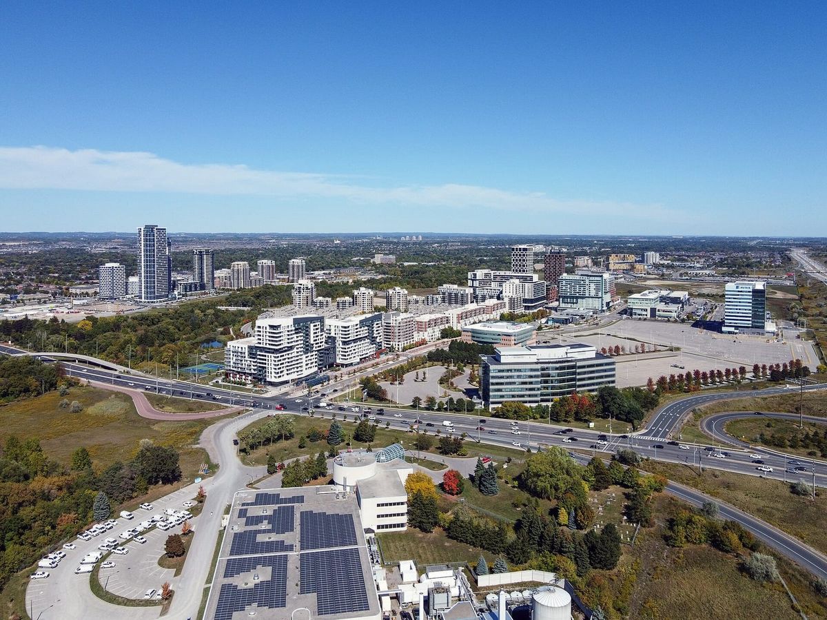 Aerial view of Downtown Markham condo towers and offices beside Highway 407 on a sunny day.
