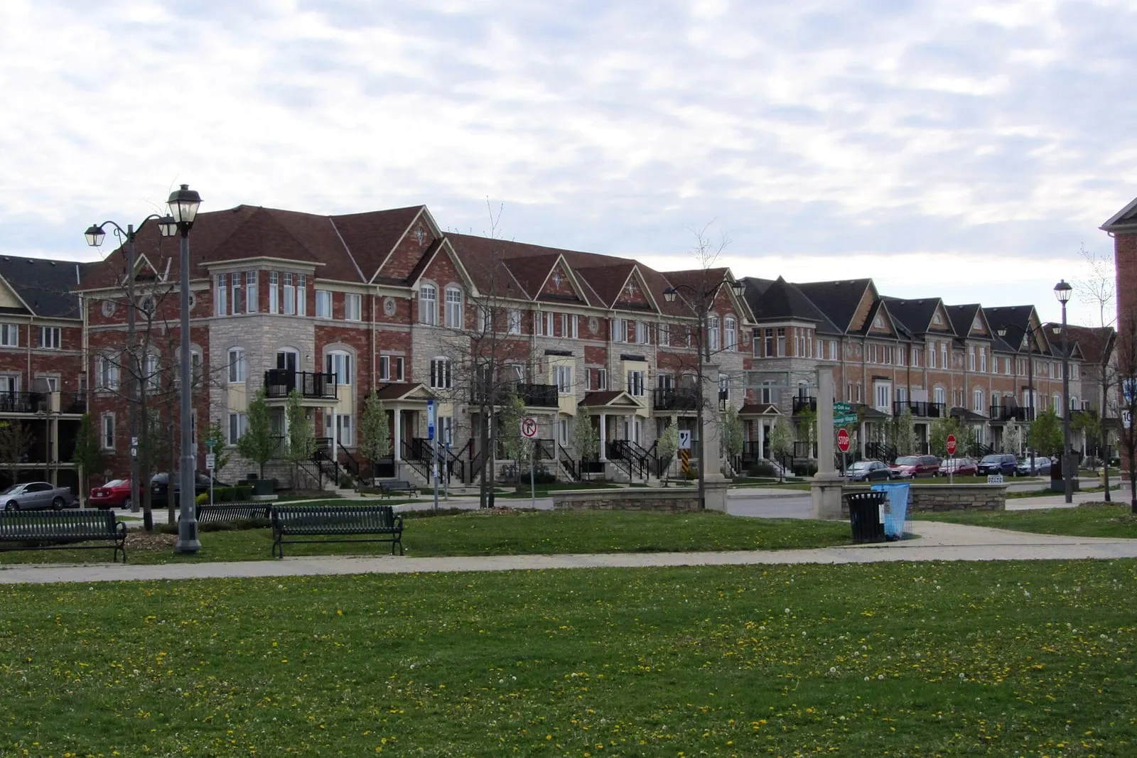Townhouses facing a park with benches in the Greensborough neighbourhood of Markham.