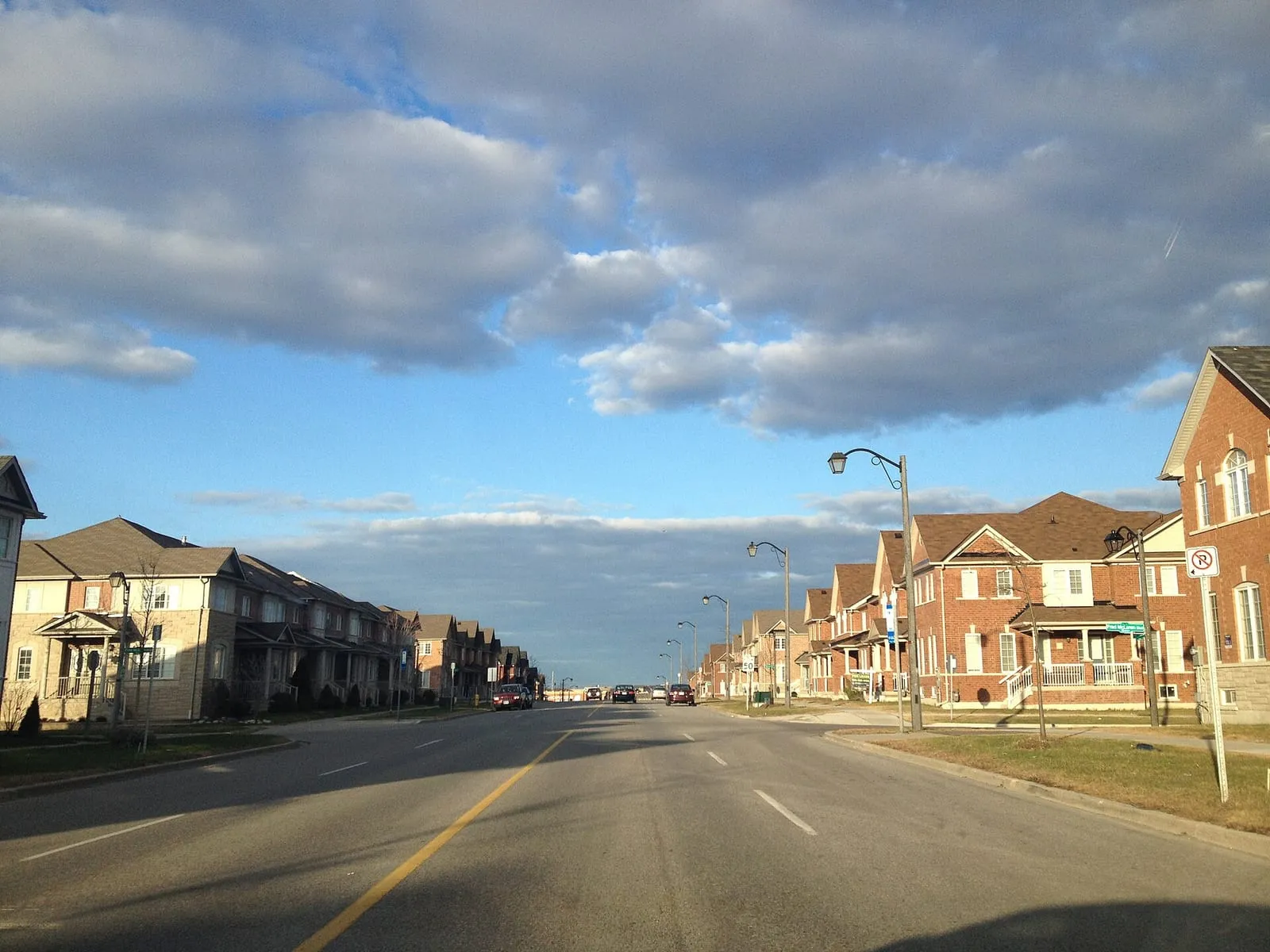 Rows of brick townhouses along Bur Oak Avenue in Wismer, Markham, under a partly cloudy sky.